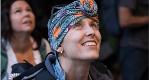 Portrait of Janice, a smiling professional woman with short curly hair and a dark blazer against a blurred background