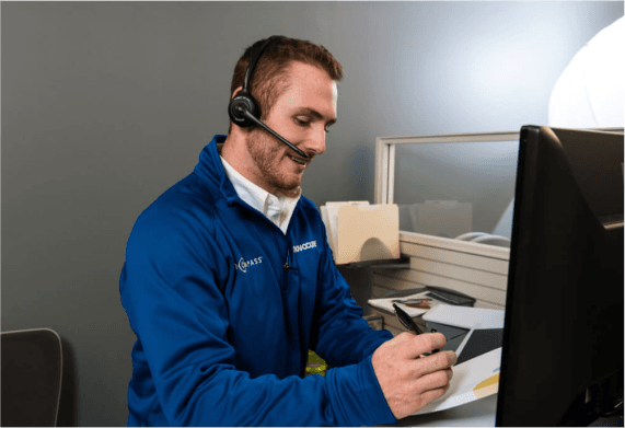 Customer service representative wearing headset and smiling while working at a desk with computer