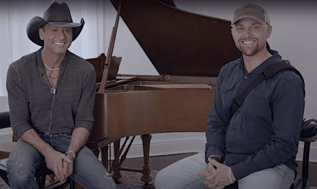 Smiling middle-aged man wearing casual blue shirt outdoors with blurred green background