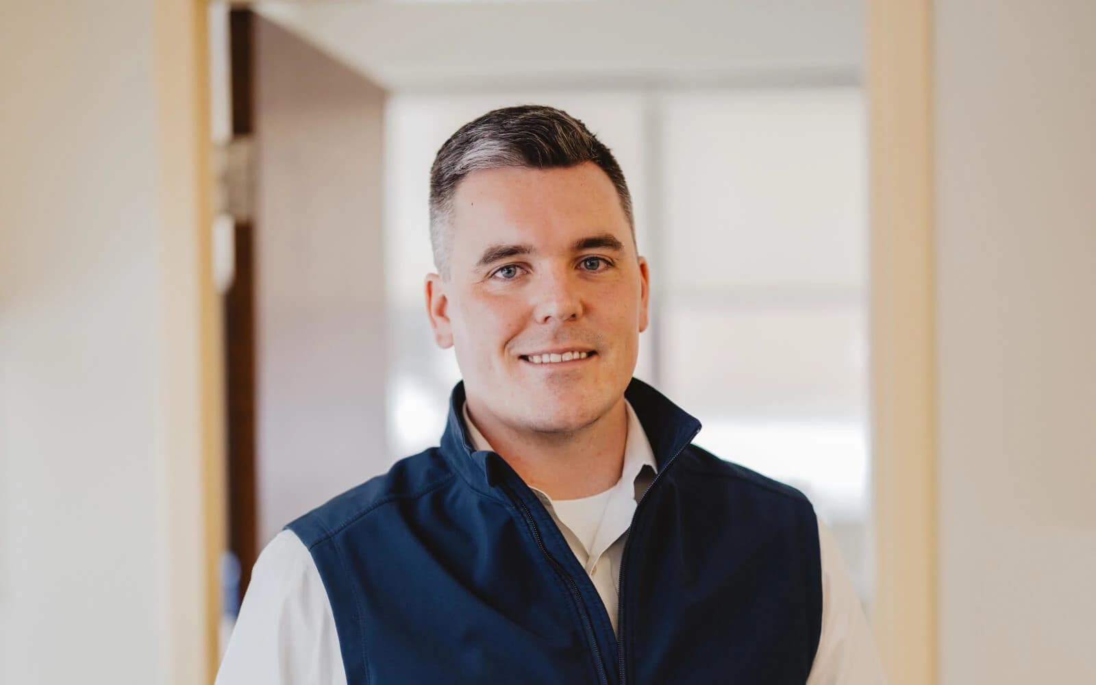 Nicholas, smiling professional man in a smart casual shirt standing confidently with arms crossed