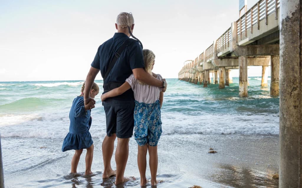 Portrait of Mike, a professional man with a confident smile wearing a checkered suit jacket and white shirt, standing against a plain background