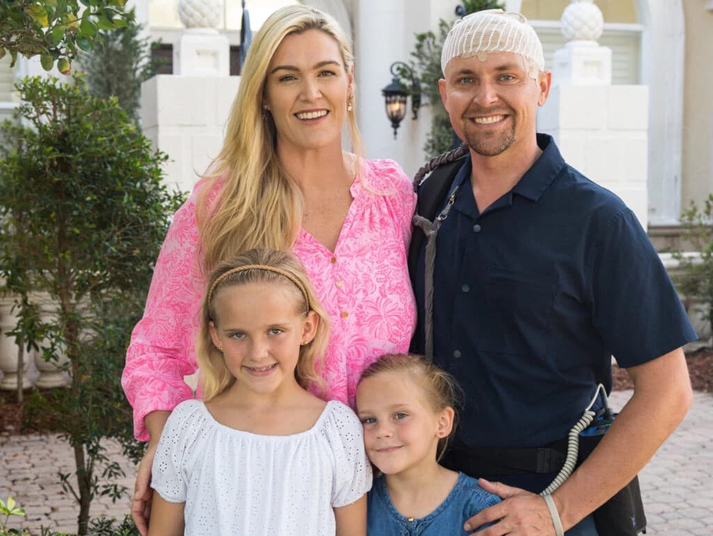 Portrait of Mike, a professional man wearing glasses and a blue shirt with arms crossed, standing confidently in a modern office environment