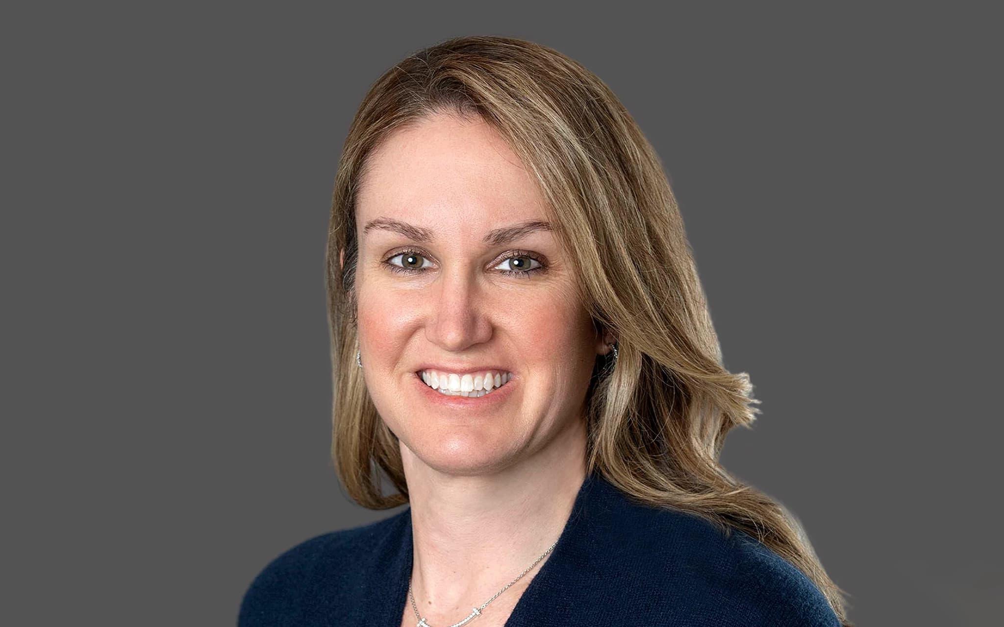 Professional portrait of Kristin, a smiling woman with blonde hair wearing a dark blazer
